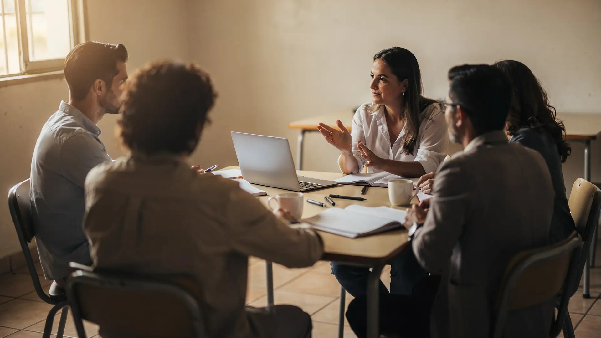 Professores reunidos em volta de uma mesa com cadernos e notebook, combinando regras de uso de IA para professores na escola.